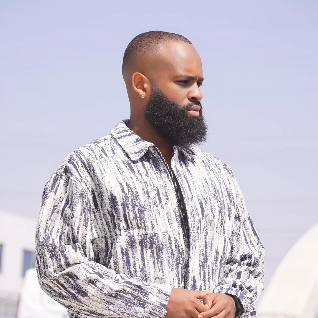 Trevor Queen in a marbled jacket photographed against open sky